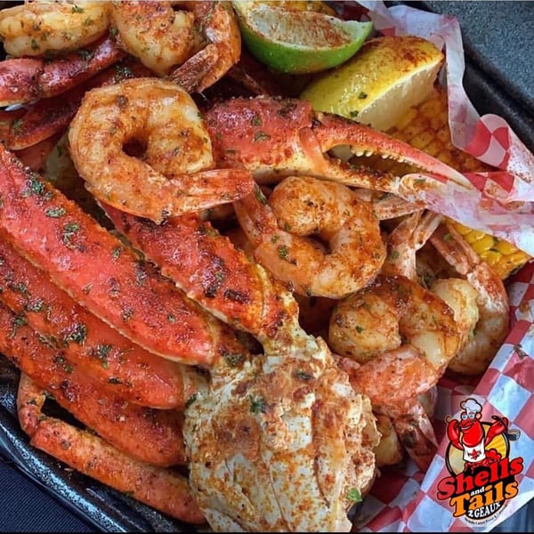 Cajun seafood boil with seasoned shrimp, crab legs, corn, and lemon wedges in a basket.